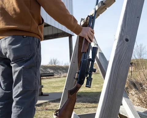 man picking up a gun with a scope at a shooting range