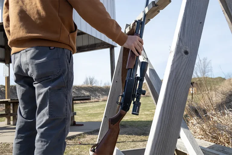 man picking up a gun with a scope at a shooting range