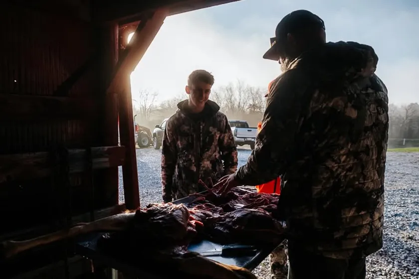 two men in a skinning shack after a hunt