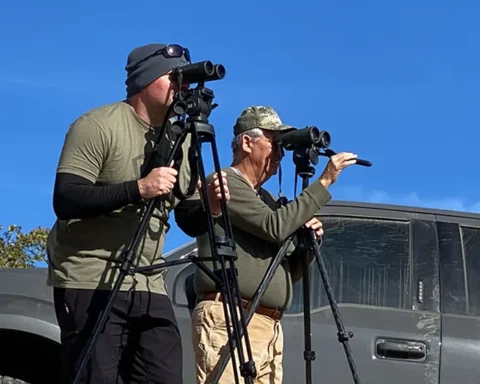 two men glassing a landscape with binos near a truck