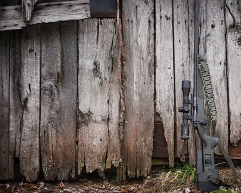 A hunting rifle leaning up against a building