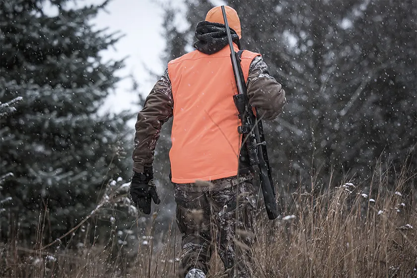 a whitetail deer hunter walking in the snow