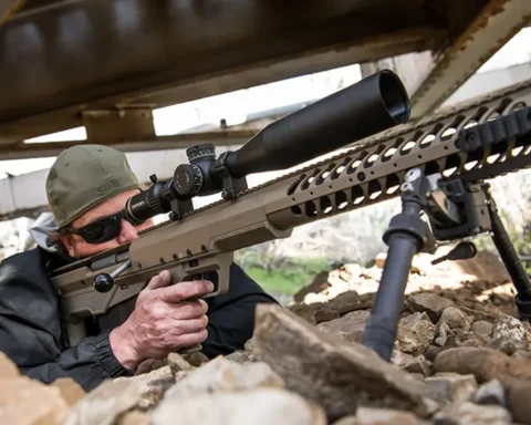Man aiming a large caliber long range rifle with a scope under a bridge