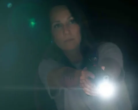a woman holding a handgun in her home at night