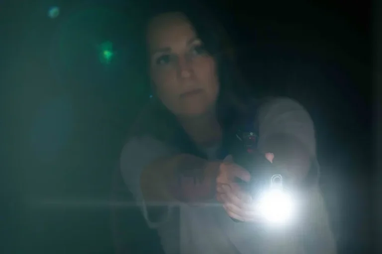 a woman holding a handgun in her home at night