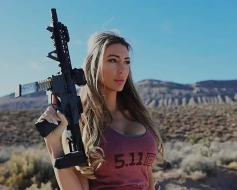 woman holding a carbine with a red dot in the desert