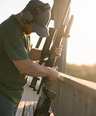 Man holding a long range rifle with a Riton Conquer scope